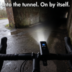 Handlebar view entering a brick underpass as the bike light comes on in sensor mode
