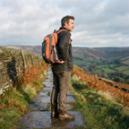 Walker on a Peak District gritstone edge taking a bottle from the side pocket of the Terrabound 40L hiking rucksack