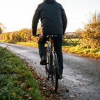 Rider freewheeling down an autumn country lane on a hybrid bike fitted with the gel bike seat