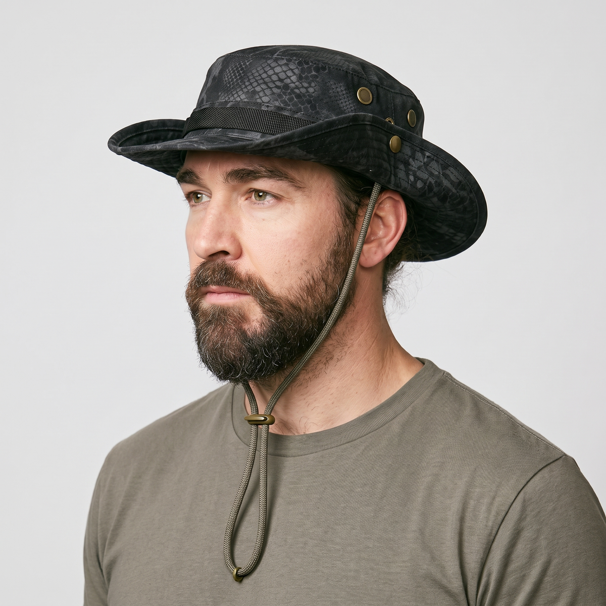 Man wearing the Terrabound men's boonie hat in black python print, three-quarter view showing the vent eyelets