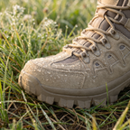 Water droplets beading on a khaki walking boot in wet grass