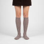 Woman wearing taupe merino wool knee high socks with a skirt