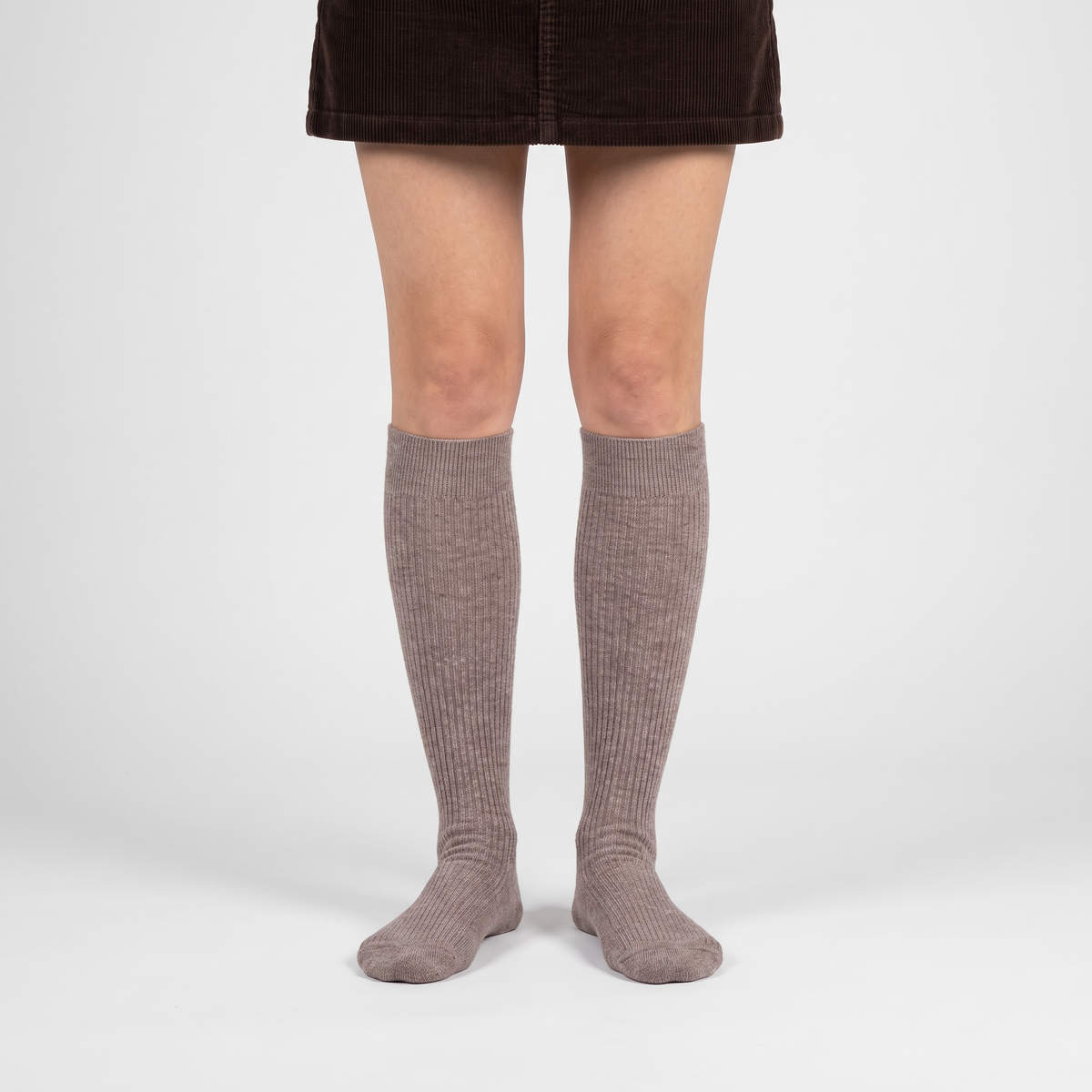 Woman wearing taupe merino wool knee high socks with a skirt