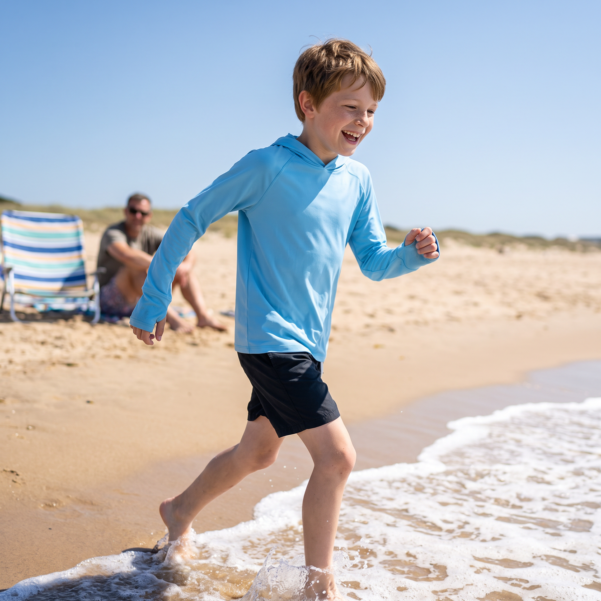 Child running on a sunny beach in the Kids' Sun Hoodie