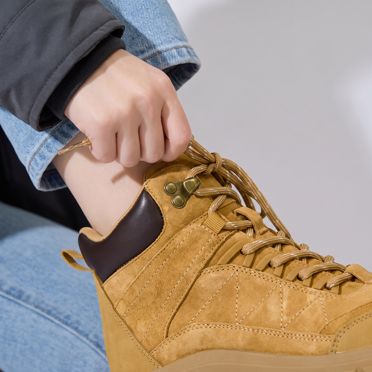 Hand pulling the lace tight through the brass speed hooks of the Women's Walking Boots