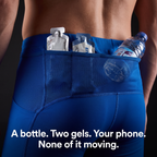 Close-up of the mesh-backed lower back pocket holding a water bottle with two energy gels in the divided waistband slots