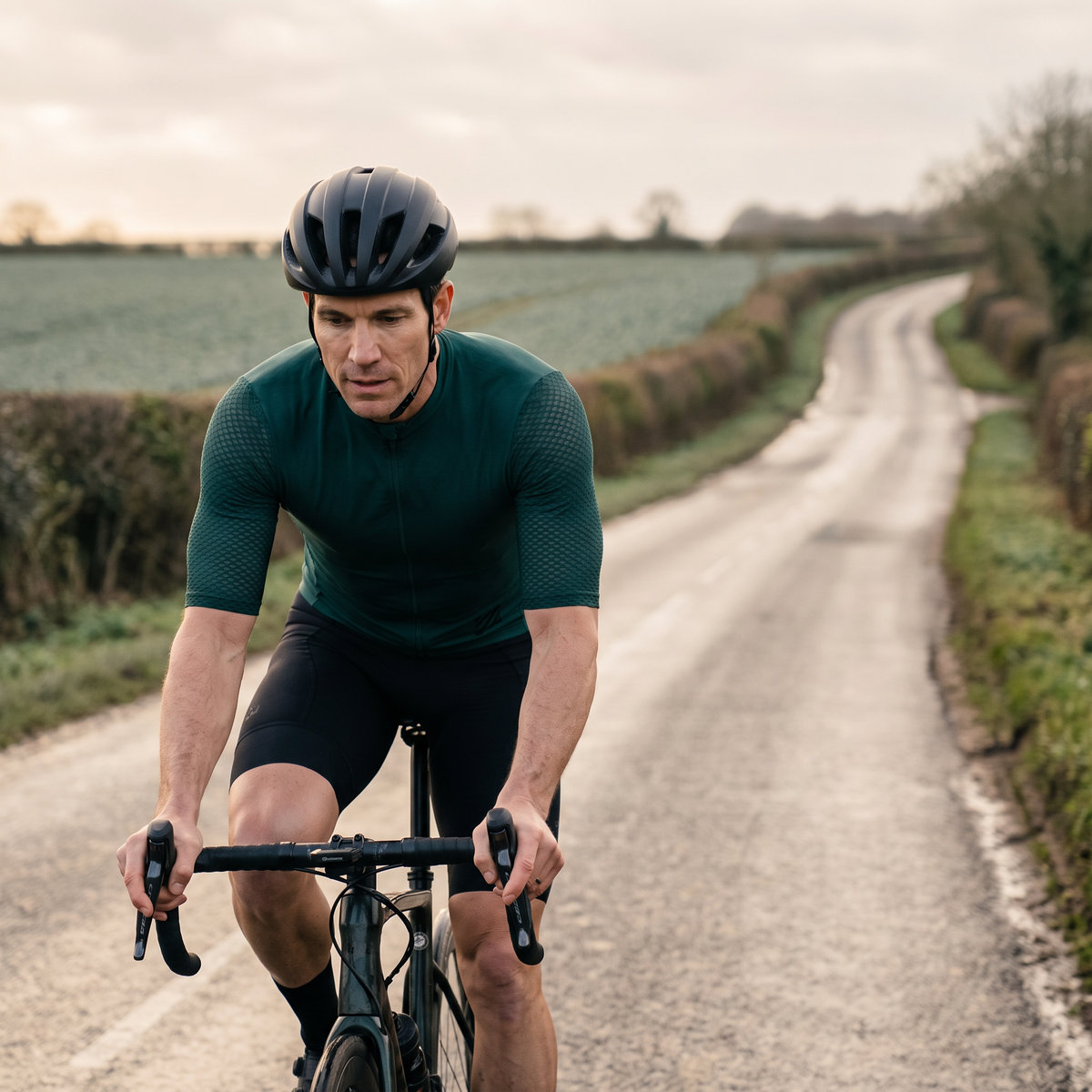 Cyclist riding a country lane in the Dark Green jersey