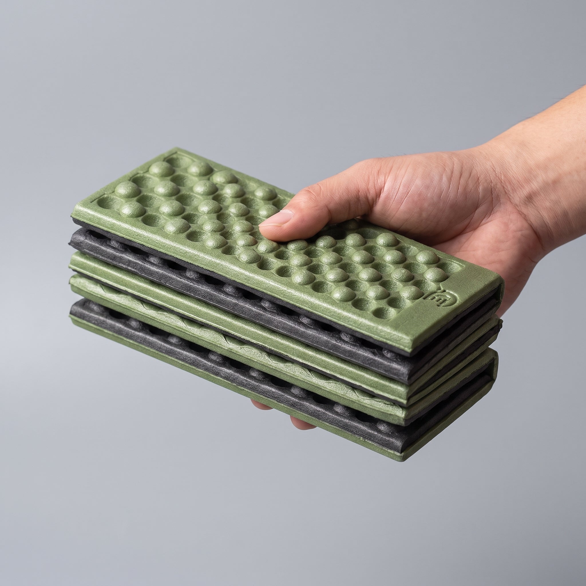The folding sit mat packed down and held in one hand