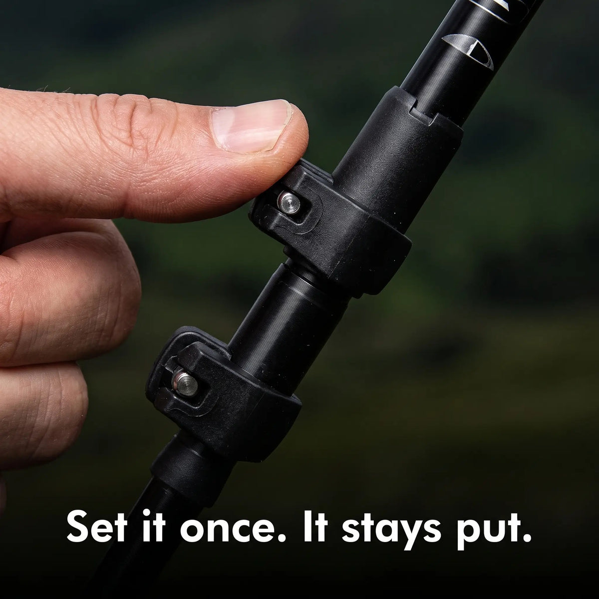 Thumb closing a lever lock on a black trekking pole