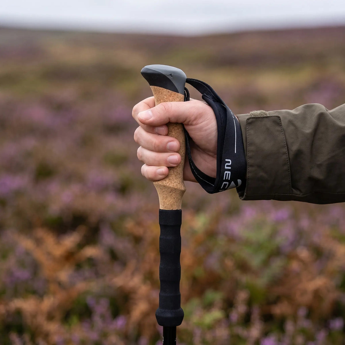 Hand in the padded wrist strap holding the cork grip of a trekking pole
