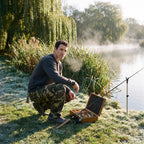 Man crouching on a riverbank in Olive Green camo cargo trousers