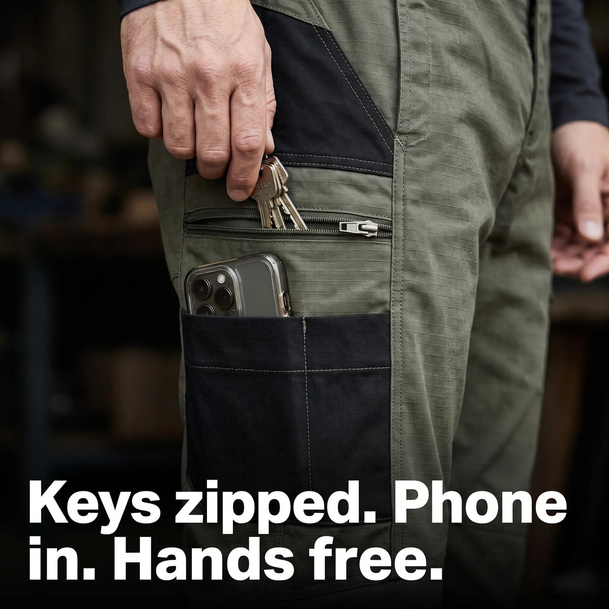 Hand zipping keys into the thigh pocket of the work trousers