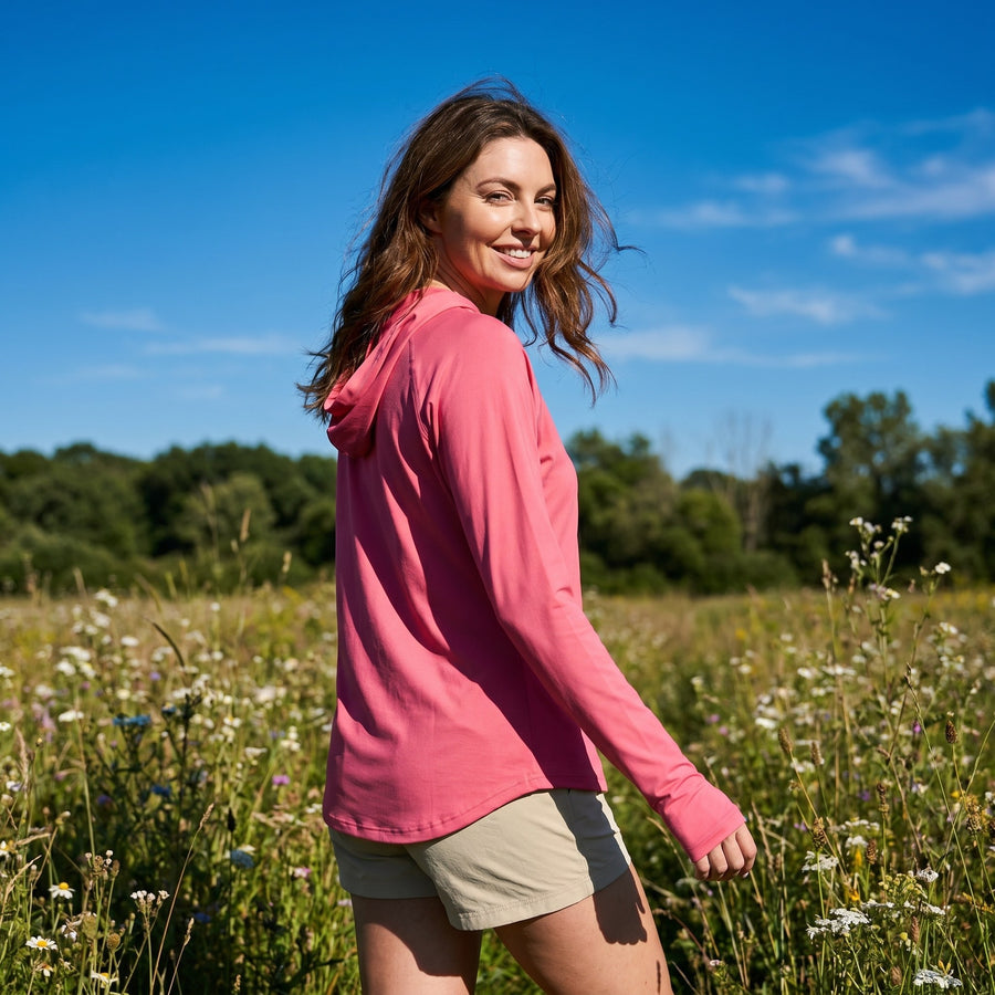 Woman walking through a summer meadow in the rose sun hoodie