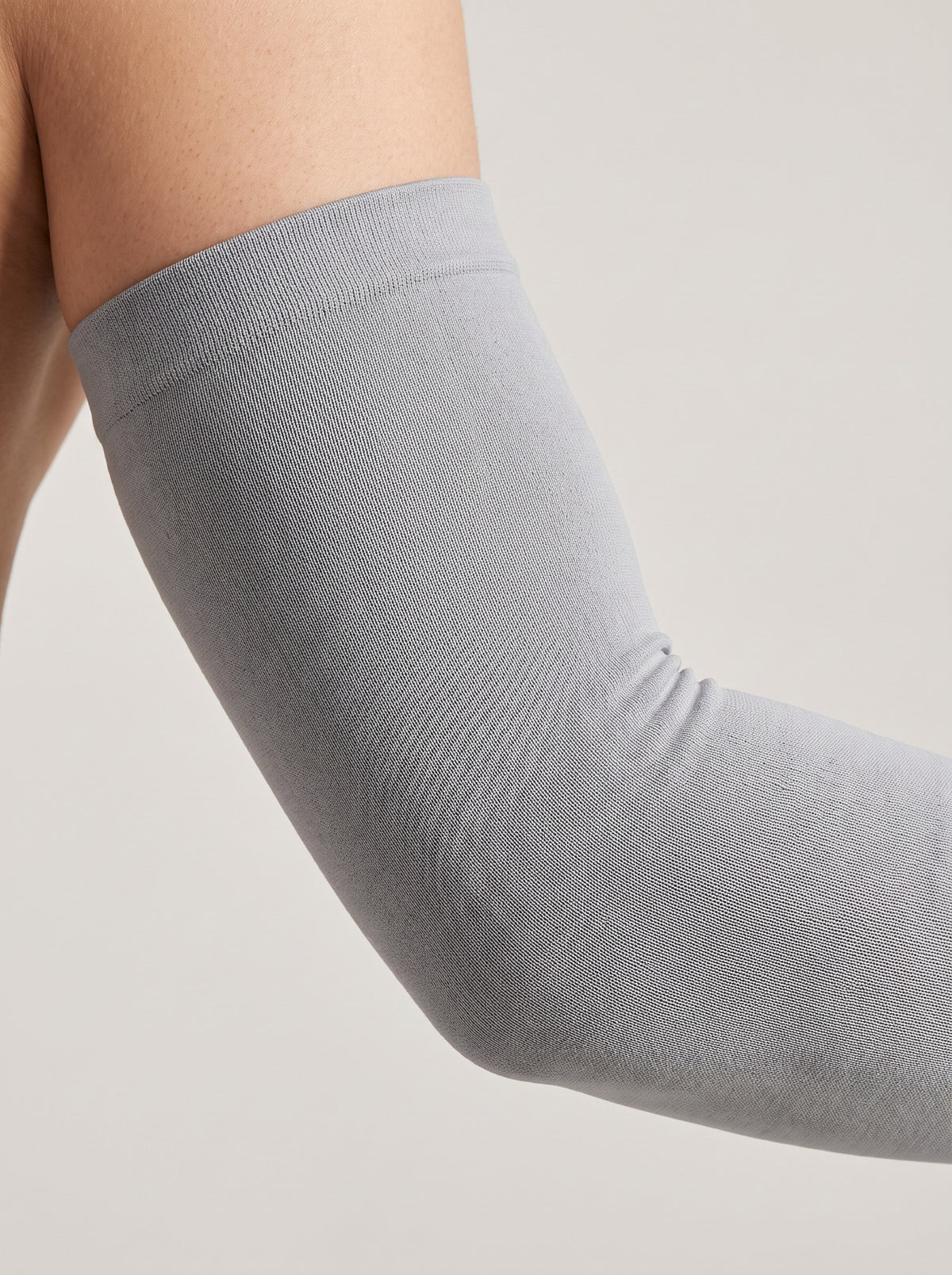 Close-up of the elasticated top band of a sun sleeve gripping the upper arm, sitting flat with no rolling or gap