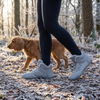 Woman walking a spaniel on a frosty woodland path in the barefoot winter boots