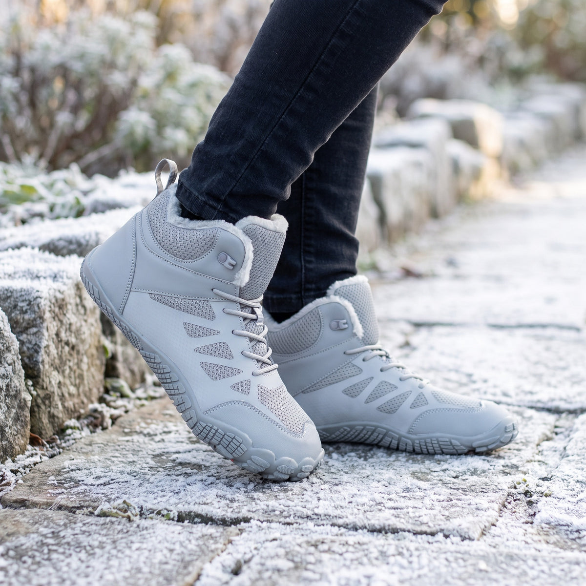 Barefoot winter boots in Grey worn on a frosty stone path