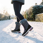Woman walking down a snowy village lane in the Grey women's winter boots