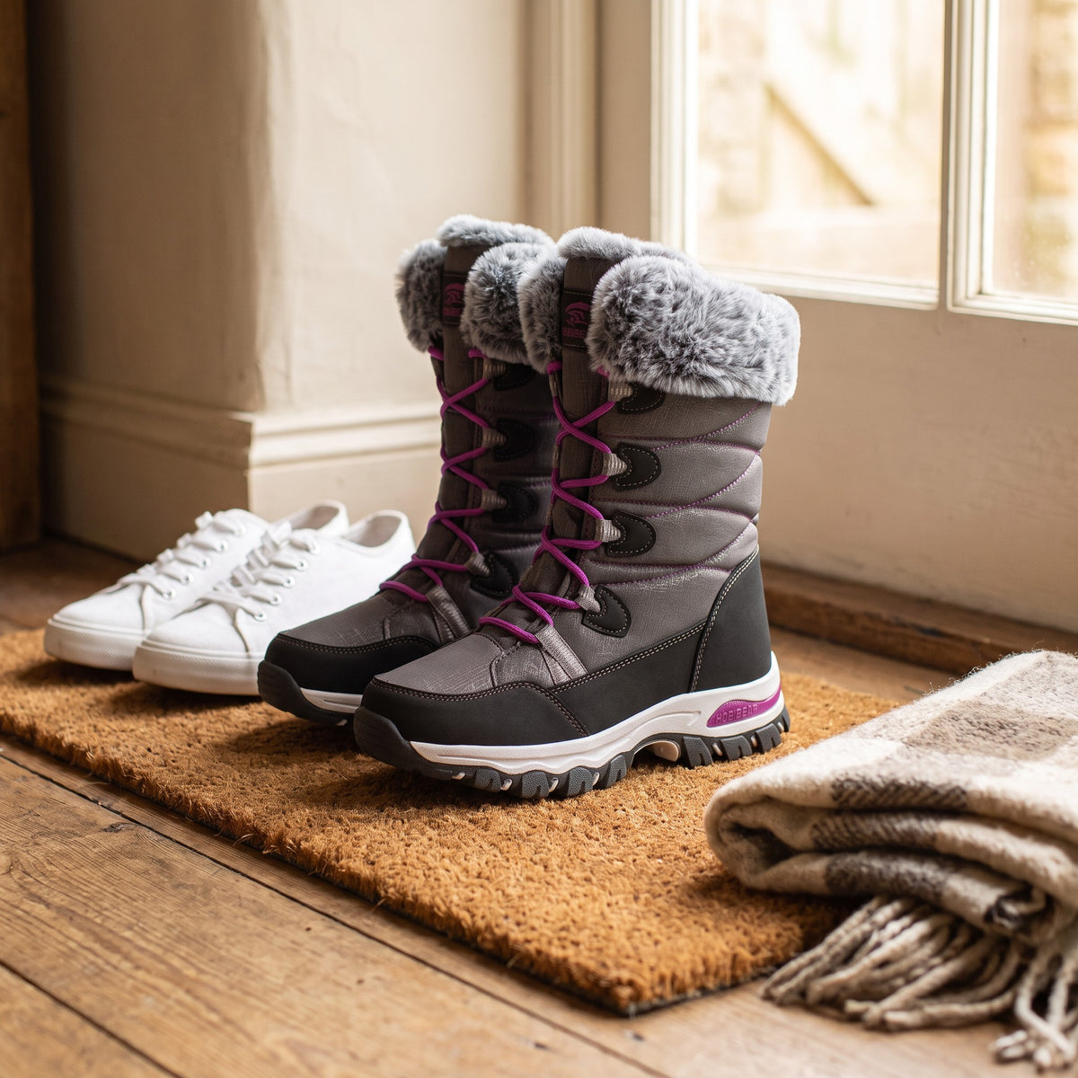 Grey snow boots beside a pair of canvas trainers to show the mid calf height