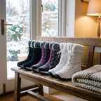 Black, Grey and White faux fur snow boots lined up on a cottage porch bench