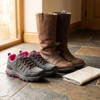 Low-cut Grey hiking shoes beside tall leather boots to show the cut