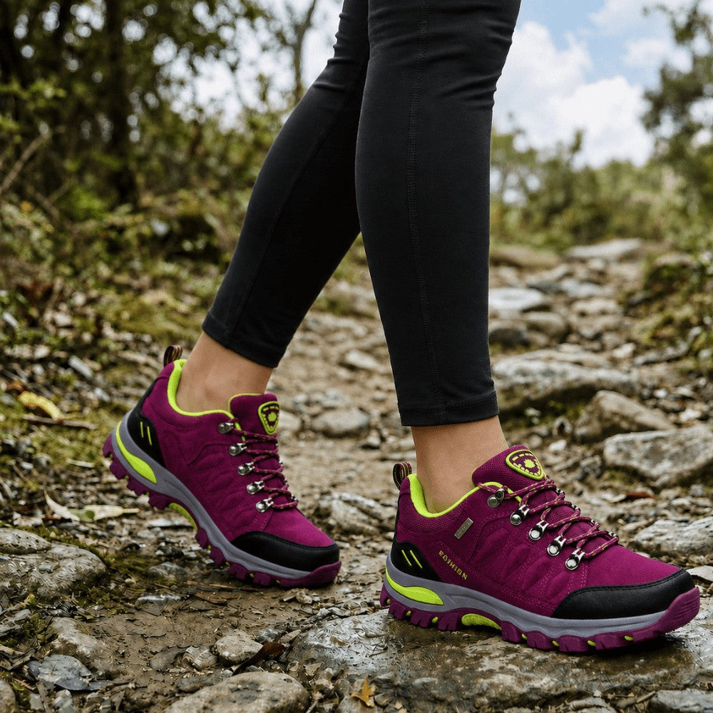Purple women's walking shoes worn on a rocky trail