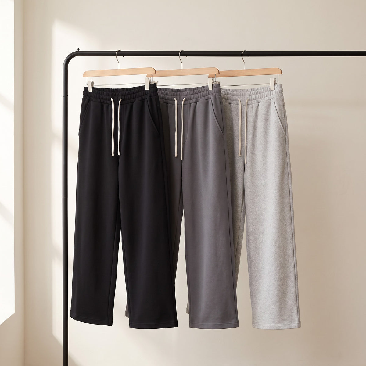 Black, Grey and Light Grey joggers hanging on a clothes rail