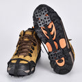 Microspikes fitted on a pair of walking boots, one sole turned up to show the spikes