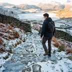 Walker on an icy Lake District path wearing microspikes on his walking boots