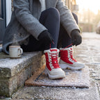 Woman lacing up the Red platform snow boots on a frosty front step