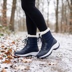 Navy women's winter boots worn on a snowy woodland path
