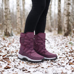 Plum winter boots for women worn with leggings on a snowy woodland path