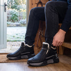 Man zipping up the side zip of his Black winter trainers by the back door