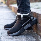 Black men's winter trainers worn with jeans on a frosty pavement