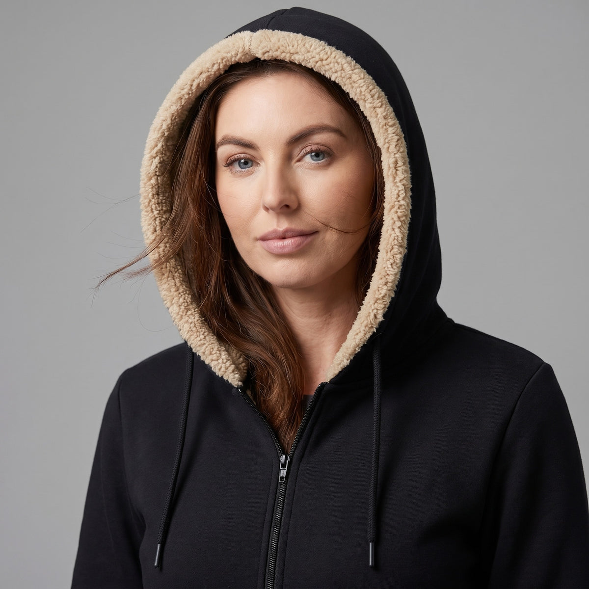 Woman wearing the sherpa lined hood up, drawcords hanging at the front