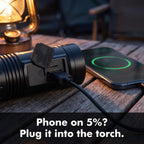 Phone charging from the torch's USB-A port on a camp table