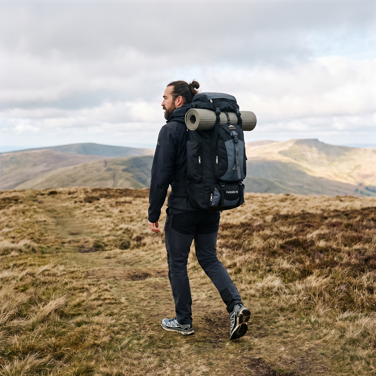 Man walking a Brecon Beacons ridge with the Terrabound 70L hiking rucksack packed and a sleeping mat strapped on