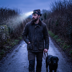 Man walking a dog on an unlit lane wearing the head torch