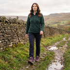 Woman walking a muddy Peak District footpath in purple walking boots