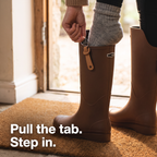 Hand pulling the back tab of the women's wellie while stepping in