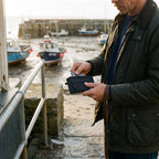 Man at a harbour kiosk sliding a bank card out of the zip card holder's front pocket
