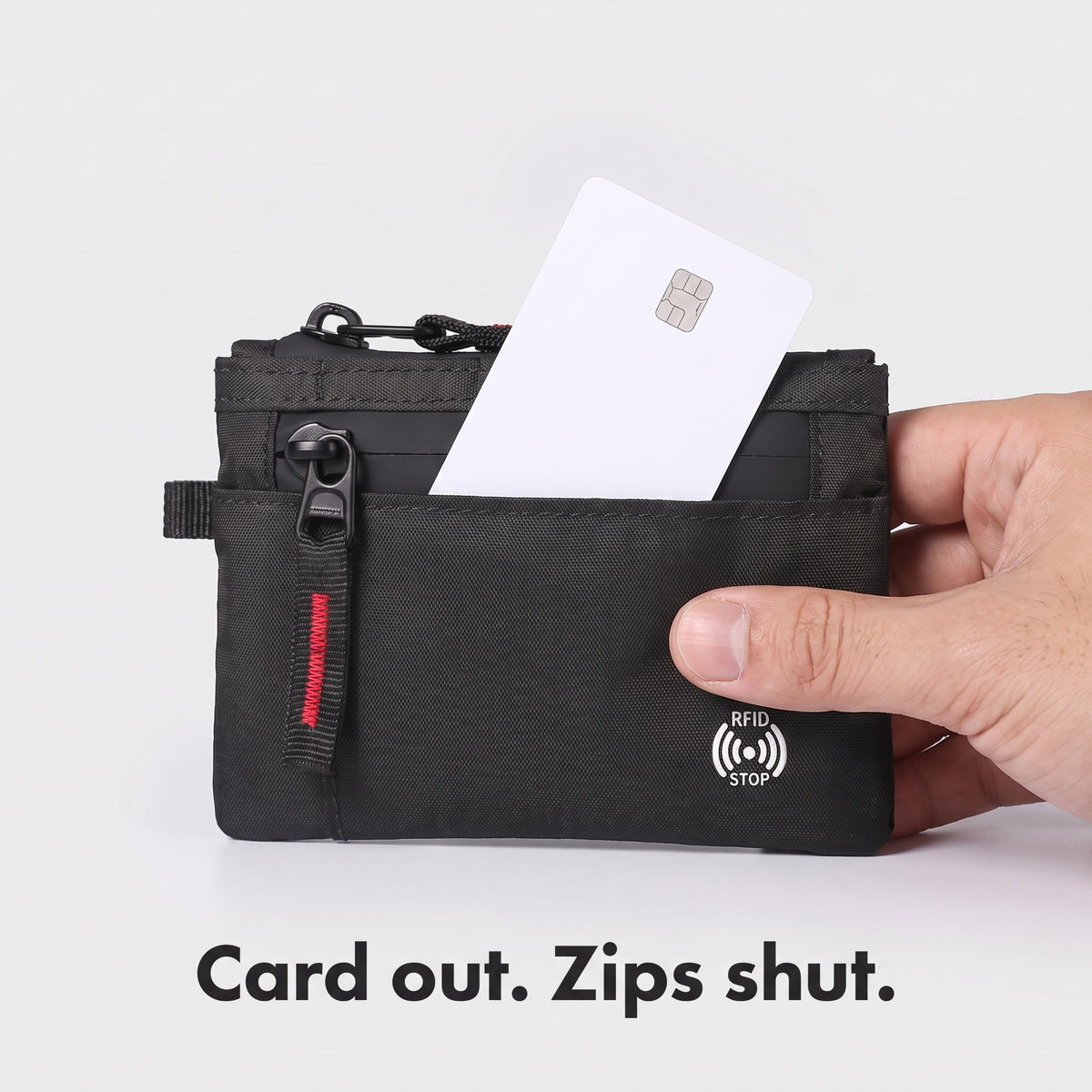 A bank card sliding out of the open front pocket with both zips shut
