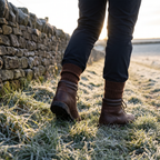 Brown wool socks worn above leather walking boots on a frosty path